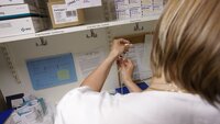 Bildet viser en sykepleier på et medisinrom som trekker opp en sprøyte.