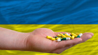 Medisiner, Ukraina Bildet viser en hånd som holder piller, i bakgrunnen ses litt av det ukrainske flagget.