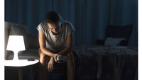 Bildet viser en kvinne som sitter på sengekanten og ikke får sove