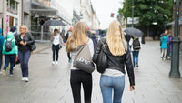 Bildet viser to unge kvinner, fotografert bakfra, som går på gaten