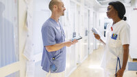 Bildet viser to sykepleiere som snakker sammen