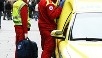 Bilde viser ambulansearbeidere som står utenfor ambulansen i et gatemiljø Bilde viser ambulansearbeidere som står utenfor ambulansen i et gatemiljø