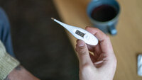 Bildet viser en person som holder et termometer