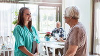 Bildet viser en sykepleier på sykehjem som snakker med en kvinnelig student