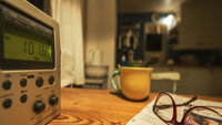 Bildet viser radio, kopp og briller på bord. Illustrasjonsfoto.