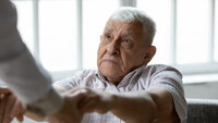 Bildet viser en eldre mann som holder hendene til noen utenfor bilderammen