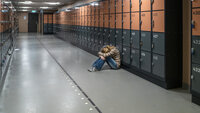 Bildet viser en ungdom som sitter i en korridor Bildet viser en ungdom som sitter i en korridor