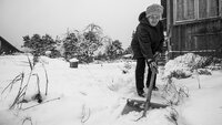 bildet viser eldre dame som måker snø