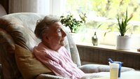 Bildet viser en eldre kvinne som sitter i en stol.