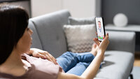 Bilde av person på sofa med mobiltelefon