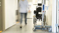 Bildet viser en pleier som går i gangen på en institusjon.