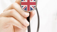 En lege som holder opp stetoskop med det engelske flagget