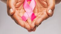 Rosa brystkreftsløyfe som holdes i hender