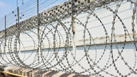 Bilde av piggtråd og gjerde rundt et fengsel Bilde av piggtråd og gjerde rundt et fengsel