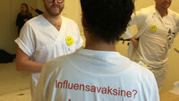 Bildet viser ryggen på en som har en t-skjorte med skriften Influensavaksine? Ja takk!
