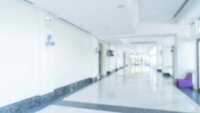 Uklart foto av hvit sykehuskorridor.