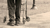 Alderdom Bildet viser en eldre mann som går med gåstol.