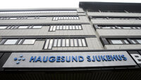Grå fasade med blått skilt der det står Haukeland sjukehus 
