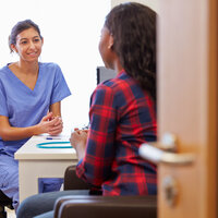 Sykepleier snakker med en kvinne på et kontor.