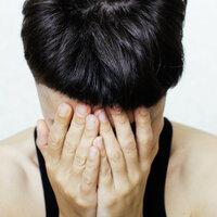 Bildet viser en ung dame eller jente som fortvilet holder hodet i hendene.