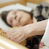 Gammel dame ligger i en seng.