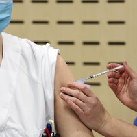 Bildet viser en helsearbeider som får koronavaksine.