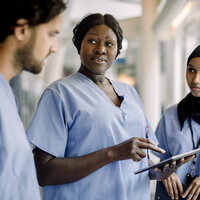 Bildet viser tre sykepleiere som står og prater sammen