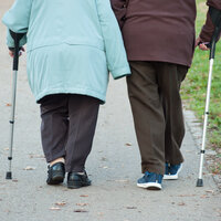 Et eldre par med spaserstokk går tur