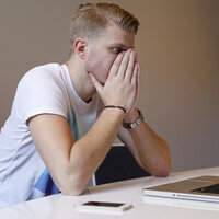 En sliten, ung mann ser på en dataskjerm