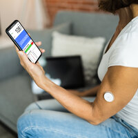 Bildet viser en kvinnelig pasient som bruker CGM (kontinuerlig glukosemåling) for å måle blodsukkeret. Verdiene sendes via bluetooth til mobilen.