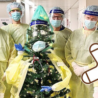 Bildet viser et juletre kledd i smittevernutstyr, omgitt av seks intensivleger.