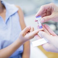 Bildet viser hender som tar en crp-prøve av en ung jente.