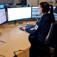 Bildet viser en AMK-sykepleier på AMK-sentralen. Hun sitter foran fire store skjermer og svarer på 113-samtaler