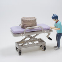 Bildet viser figurerer av en portør som triller en tom båre med mynter