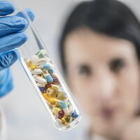 Bildet viser en kvinne som holder opp et glassrør med piller.