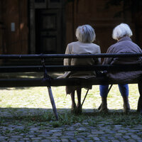 Bildet viser to eldre kvinner som sitter på en benk