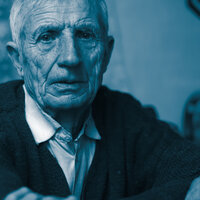 Bildet viser et nærbilde av en eldre mann som kikker inn i kameraet. Han ser trist ut