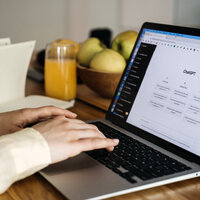 Bildet viser et par hender som skriver på et pc-tastatur. På pc-skjermen står det ChatGPT.