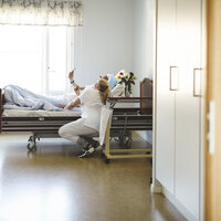 Bildet viser en sykepleier og en pasient som ser på mobilen sammen