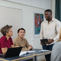 Bildet viser en lærer som diskuterer med tre elever