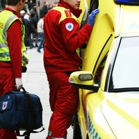 Bilde viser ambulansearbeidere som står utenfor ambulansen i et gatemiljø
