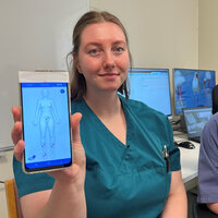 Bildet viser to sykepleiere som viser frem en mobilapp.