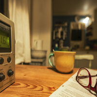 Bildet viser radio, kopp og briller på bord. Illustrasjonsfoto.