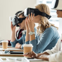Bildet viser studenter med VR-briller på. De sitter ved sine pulter i et klasserom
