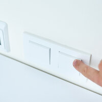 Bildet viser en finger som slår av en lysbryter.