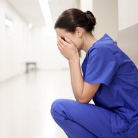 Bildet viser en stresset og sliten sykepleier