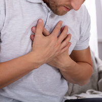 Mann med smerte i brystet holder hendene mot brystet.