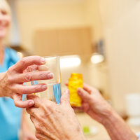 Pasient får medikamenter av pleier.