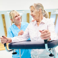 Sykepleier og eldre kvinne med gåstol