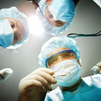 Tre kirurger kikker ned på en pasient